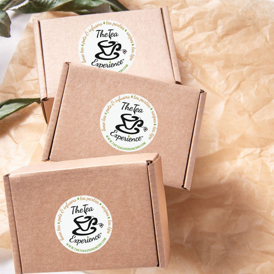 three brown cardboard boxes with 'The Tea Experience' logo on a textured beige background